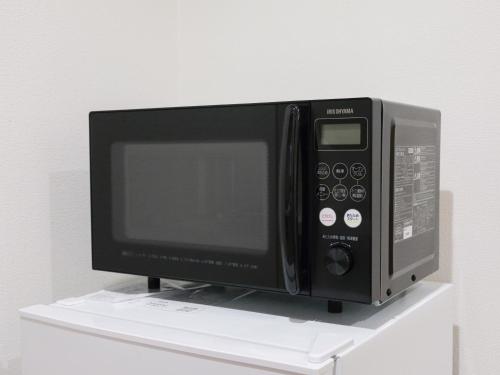 a microwave oven sitting on top of a shelf at 期間限定セール中 - The River Up Palace -ザリバーアップパレス- 三井ｱｳﾄﾚｯﾄﾊﾟｰｸ木更津徒歩9分 ﾌﾟﾛｼﾞｪｸﾀｰや駐車場付の1LDK in Kisarazu