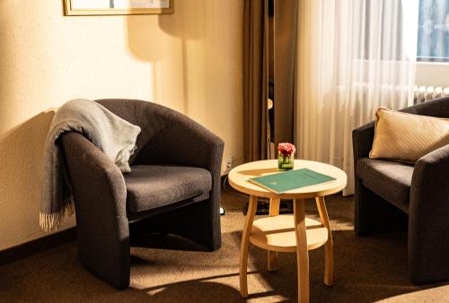 a living room with two chairs and a table at Eibsee Hotel in Grainau