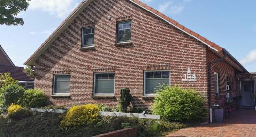 a red brick house with windows and bushes at Ferienwohnung Sternenkieker in Krummhörn