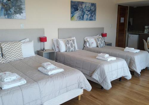 a room with three beds with towels on them at Apart Hotel Quijote by DOT Suites in Ciudad Lujan de Cuyo
