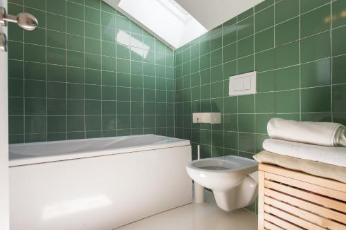 e bagno piastrellato verde con servizi igienici e vasca. di FLH Melides Beach House a Melides