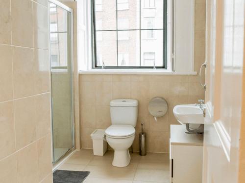 a bathroom with a toilet and a sink and a window at Gardiner House Hostel in Dublin