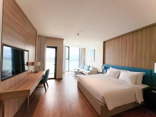 a bedroom with a bed and a desk and a television at OceanView Alacarte Hạ Long in Ha Long
