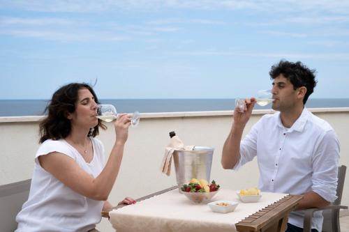 a man and a woman drinking wine at a table at Hotel Mondial in Bellaria-Igea Marina
