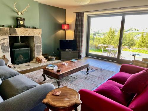 a living room with a couch and a fireplace at Railway Cottage in Killin