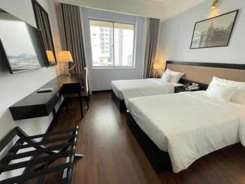 a hotel room with two beds and a desk at Thien Hong - Arc En Ciel Hotel in Ho Chi Minh City