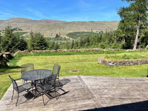 a table and chairs sitting on a deck with a view of a field at Railway Cottage in Killin