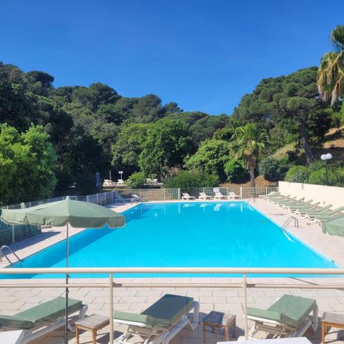 une grande piscine avec des chaises et un parasol dans l'établissement La Joya de Villepey, à Saint-Aygulf