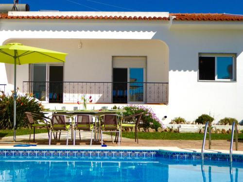 a house with a table and chairs next to a swimming pool at Vital by Check-in Portugal in Albufeira