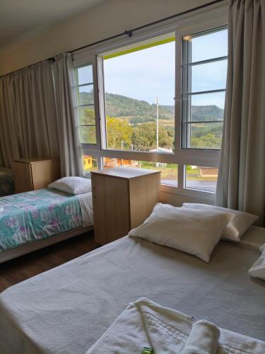 a bedroom with two beds and a large window at Hospedaria Bom Pastor in Nova Petrópolis