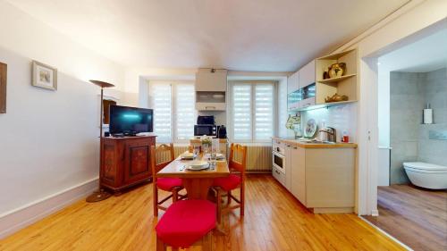 a kitchen with a table and red chairs in a room at Le Clos bartholdi in Colmar