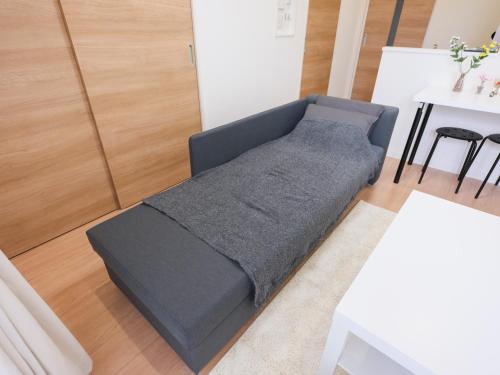 a bed in a living room next to a table at 期間限定セール中 - The River Up Palace -ザリバーアップパレス- 三井ｱｳﾄﾚｯﾄﾊﾟｰｸ木更津徒歩9分 ﾌﾟﾛｼﾞｪｸﾀｰや駐車場付の1LDK in Kisarazu