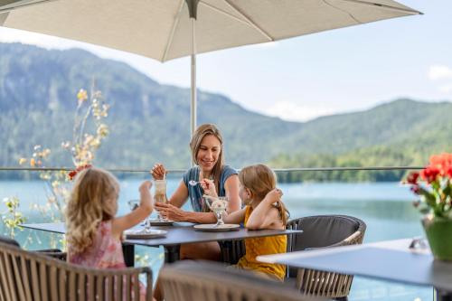 a woman and two children sitting at a table at a restaurant at Eibsee Hotel in Grainau