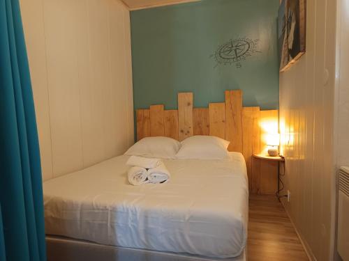 une chambre avec un lit blanc avec une tête de lit en bois dans l'établissement L'Harmonie à 2 pas de la plage - 2 chambres - Terrasse, à Saint-Georges-de-Didonne