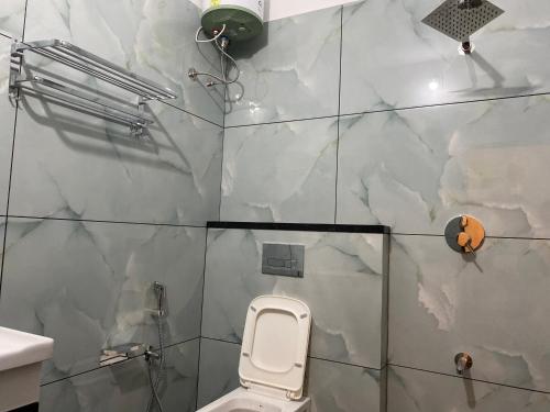 a bathroom with a toilet and a wall with marble tiles at Empire Mona Villa in Wayanad