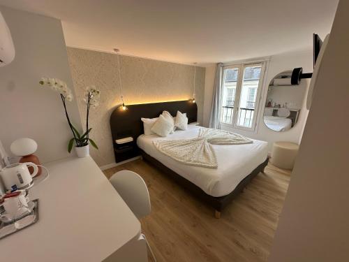 - une chambre avec un lit avec des draps blancs et une table dans l'établissement Hôtel Opera Deauville, à Paris