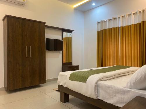 a bedroom with a bed and a wooden cabinet at Empire Mona Villa in Wayanad
