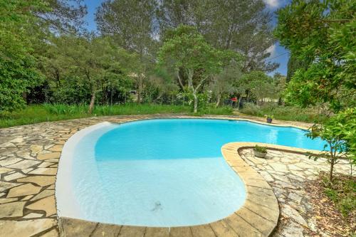 une piscine entourée d'un chemin en pierre dans l'établissement Garrigue de Nîmes - Climatisé avec piscine partagée, à Nîmes