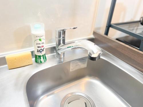a sink with a bottle of soap next to it at Prevoyance前原中央 in Itoshima