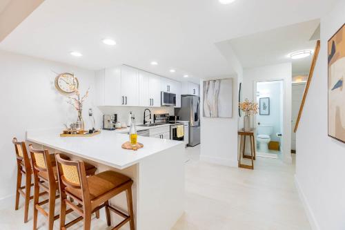 a kitchen with white cabinets and a kitchen island with chairs at Gorgeous Beach Front Condo Near Flagler Ave - 701 in New Smyrna Beach