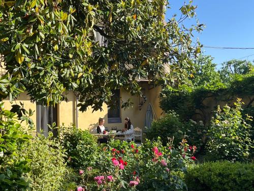 two people sitting at a table in a garden at Lunafragola Atelier B&B in Candia Canavese