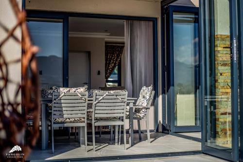 a table and chairs on a balcony with glass doors at Twelve Tumbleweed, Cathkin Estates by Euphoric Leisure in Champagne Valley