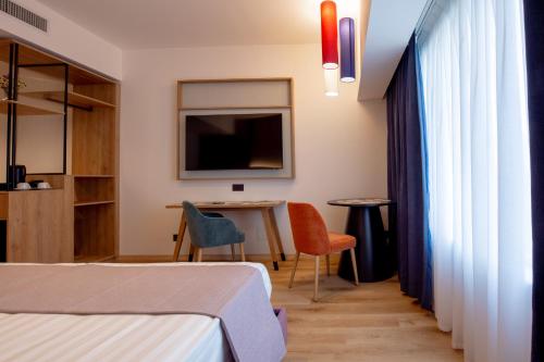 una camera con due letti, un tavolo e una televisione di Hotel Poseidon a Torre del Greco