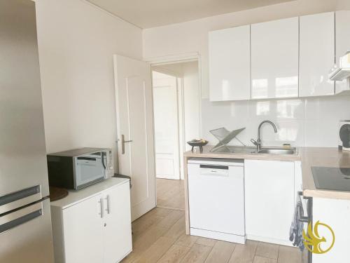 une cuisine blanche avec des armoires blanches et un micro-ondes dans l'établissement Élégant 3 pièces proche Paris La Défense, à Bezons