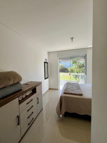 ein Schlafzimmer mit einem Bett, einer Kommode und einem Fenster in der Unterkunft Casa prox. a praia do Campeche in Florianópolis