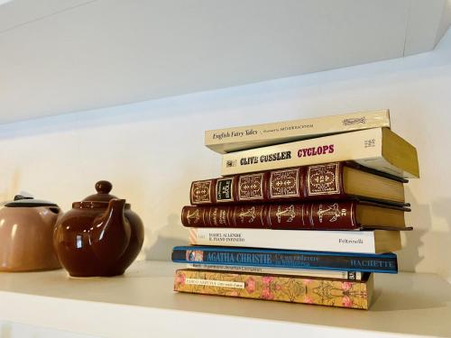 a stack of books sitting on a shelf with a vase at Casina 57 in Loro Ciuffenna