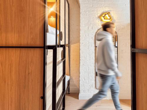 a man walking through a room with a mirror at Gardiner House Hostel in Dublin