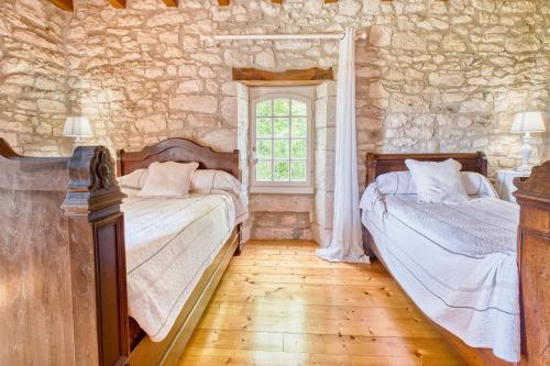 - 2 lits dans une chambre avec un mur en pierre dans l'établissement Maison de Campagne à Cunèges, à Cunèges