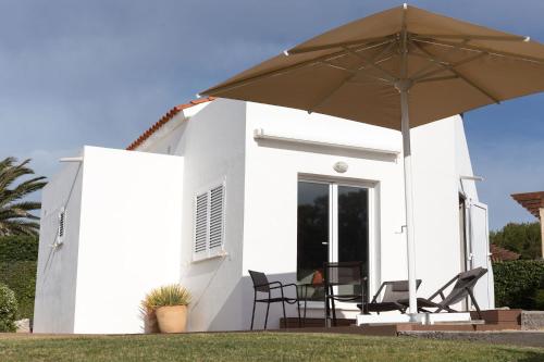 a white house with two chairs and an umbrella at BINIPARADISE Villas in Binibeca