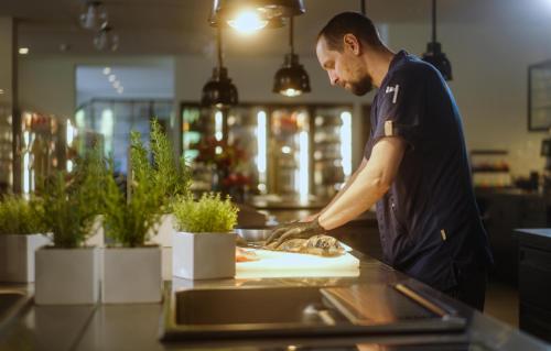 a man preparing food on a counter in a kitchen at Eibsee Hotel in Grainau