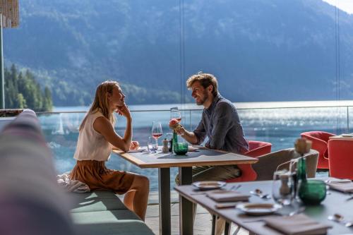 a man and woman sitting at a table with wine glasses at Eibsee Hotel in Grainau