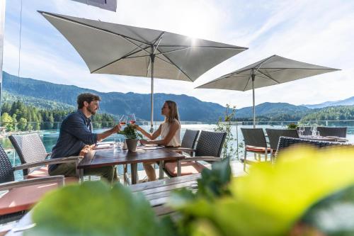 a man and woman sitting at a table under an umbrella at Eibsee Hotel in Grainau