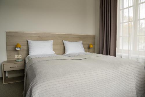 a bedroom with a large bed with white sheets and a window at Birštono Banginukas poilsio namai in Birštonas