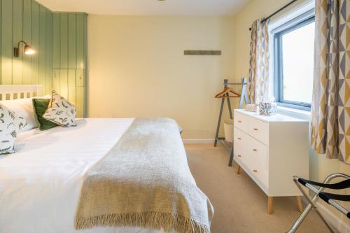a bedroom with a bed and a window and a dresser at The Tack Room in Stowmarket