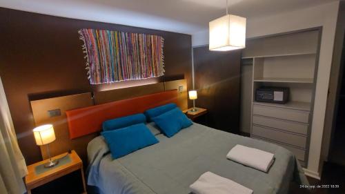 Un dormitorio con una cama grande con almohadas azules. en Belgrano Decks, en San Carlos de Bariloche