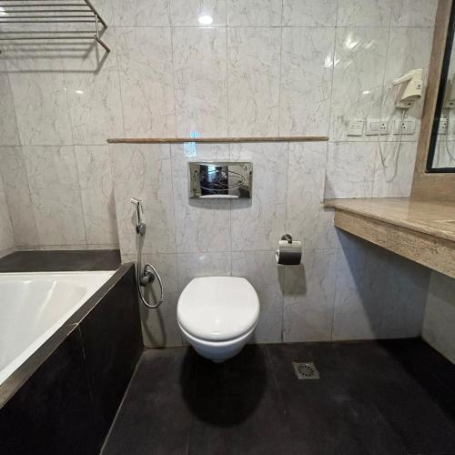 a bathroom with a toilet and a sink and a tub at The Grand Paramont Near Delhi Airport Free Airport Drop in New Delhi