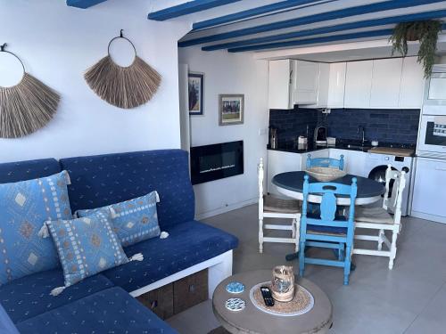a living room with a blue couch and a kitchen at Casita pescadores recién reformada frente al mar in Torrenostra