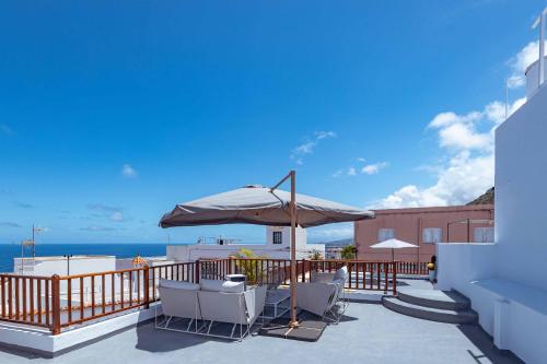 a patio with chairs and an umbrella and the ocean at Casa Justina in Garachico