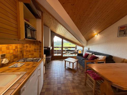 une cuisine et un salon avec un canapé et une table dans l'établissement Les Saisies - Grand Studio Cabine 4 pers avec balcon sud - FR-1-293-117, aux Saisies