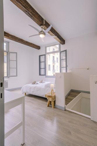 a white bedroom with a bed and a ceiling fan at L'Echauguette d'Uzès by Les Demeures de Rachel in Uzès