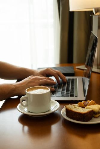 a person typing on a laptop with a cup of coffee at Blank Hotel Recoleta in Buenos Aires