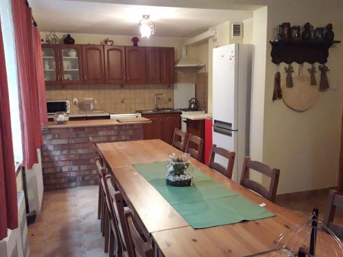 a kitchen with a wooden table and a white refrigerator at Wczasy na Kaszubach, balia, sauna, jezioro in Wąglikowice