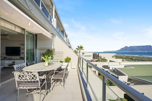 a balcony with a table and chairs and a tennis court at Dolphin Beach H106 by Host Agents in Bloubergstrand