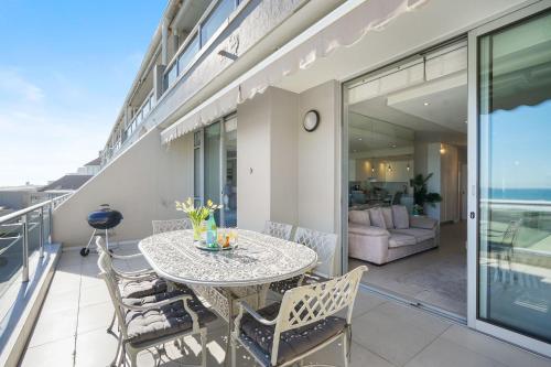 a patio with a table and chairs on a balcony at Dolphin Beach H106 by Host Agents in Bloubergstrand