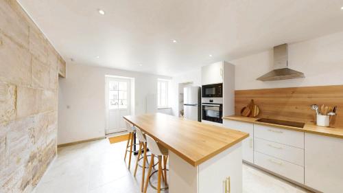 une cuisine avec des armoires blanches et un comptoir en bois dans l'établissement La Nacrière Maison Bourg de Mer 3 Chambres, à Courseulles-sur-Mer