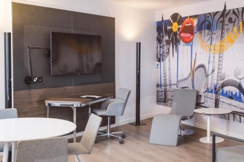 a meeting room with tables and chairs and a tv at Novotel London Excel in London